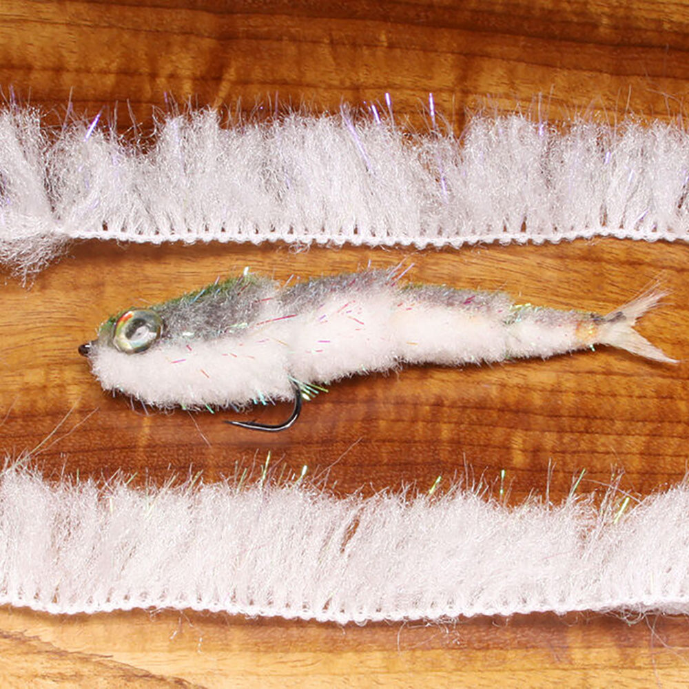 Two strips of Minnow Body Wrap in UV White shown with a GameChanger Fly  in the middle  on a wooden table