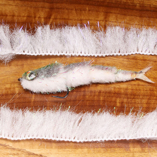Two strips of Minnow Body Wrap in UV White shown with a GameChanger Fly  in the middle  on a wooden table