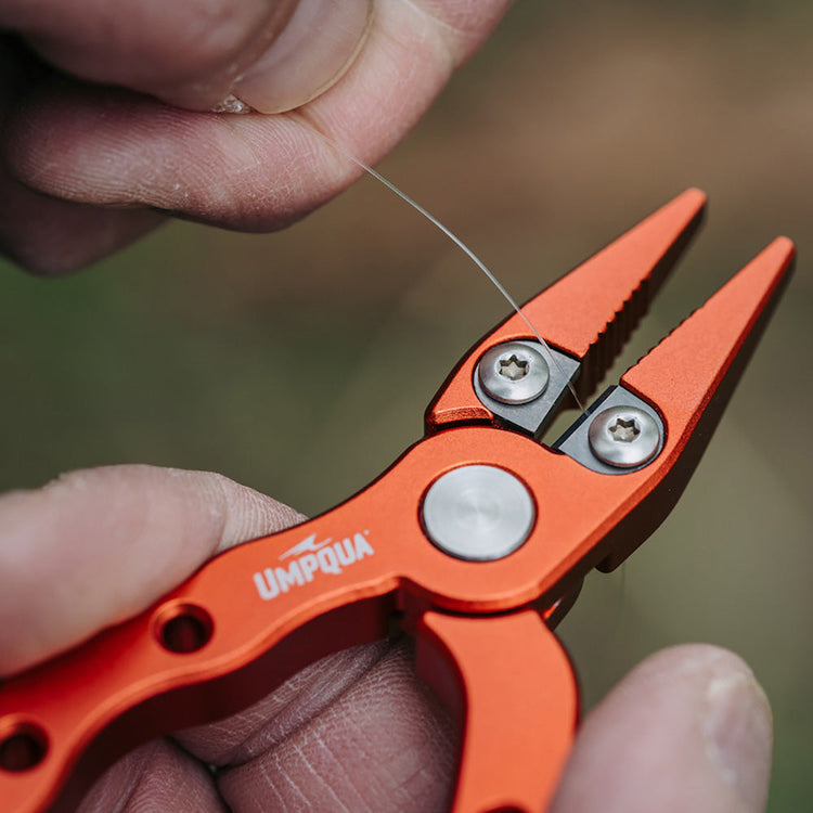 Close-up of cutting leader material with Umpqua Trout Pliers with detailed jaw design for fly fishing
