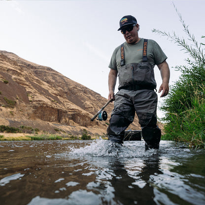 Grundens Vector Stockingfoot waders shown from the front on a man wading on a stream carrying a spey rod