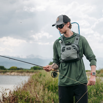 Umpqua ThunderCreek Chest Pack, Swiftlink chest pack, showing an angler holding a fly rod and wearing the chest pack