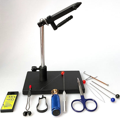 Griffin Montana Pro II Fly Tying vise with black pedestal base and an array of fly tying tools laid out on a black surface including scissors, a bobbin, a red threader, a blue hair stacker, and bodkin.